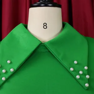 Close-up detail of a vibrant green pencil dress with an elegant pearl-studded collar