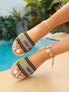 Sandalias planas de estilo étnico para mujer con bordados coloridos en fondo de playa