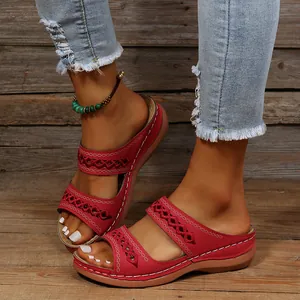 Gros plan de sandales à plateforme rouges brodées vintage portées avec un jean denim