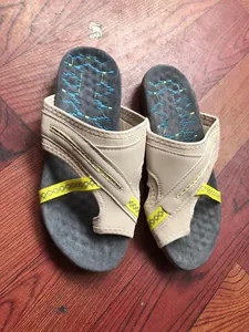 Dettaglio dall'alto di sandali infradito beige casual con cinturini incrociati e accenti gialli