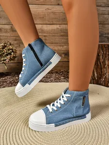 Detail van denim high-top canvas sneakers met zijrits en een dikke plateauzool.