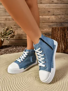 Detailopname van blauwe denim hoge platform canvas schoenen met rits aan de zijkant.