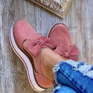 Detailed view of stylish pink suede platform sandals with a large decorative bow