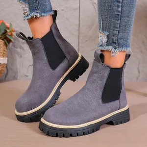 Vista detallada de botines Chelsea de ante gris con suelas negras dentadas