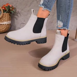 Detalle de botines Chelsea de ante gris claro con paneles elásticos negros y suelas gruesas.