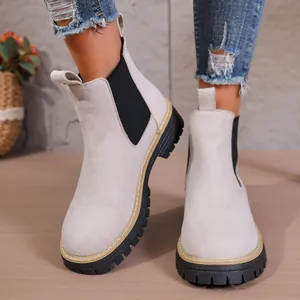 Vista detallada de botines Chelsea de ante beige con suela gruesa sobre un modelo real