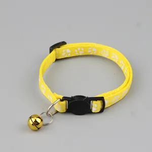 Detail van gele nylon kattenhalsband met pootjespatroon en een gouden belletje eraan