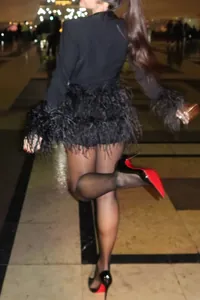 Πίσω όψη μαύρου μακρυμάνικου blazer romper με πολυτελή φτερά κατά τη διάρκεια της νύχτας