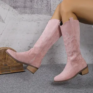 Détail de bottes de cowboy roses en daim avec motifs brodés et talon épais confortable.
