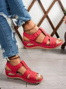 Detail of red retro wedge sandals with laser-cut hollow design