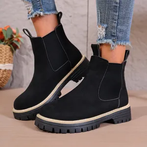 Detalle de botines Chelsea de ante negro con suelas gruesas y paneles elásticos