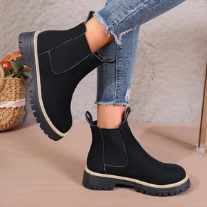 Detalle de botas Chelsea de ante negro con suela gruesa y costuras de contraste