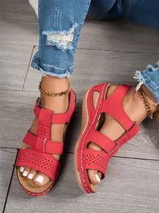 Close-up detail of red vintage sandals with floral cut-outs and white stitching
