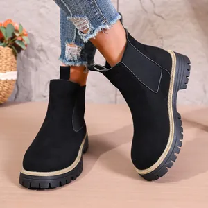 Primer plano de botines Chelsea negros de ante con suelas dentadas y paneles elásticos.