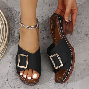 Una vista dettagliata dei sabot neri da donna con tacco largo e fibbia dorata chic.