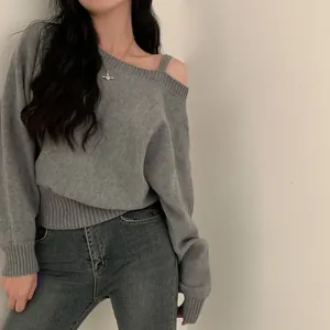 Vista dettagliata di un elegante maglione in maglia grigio con spalle scoperte e vestibilità.