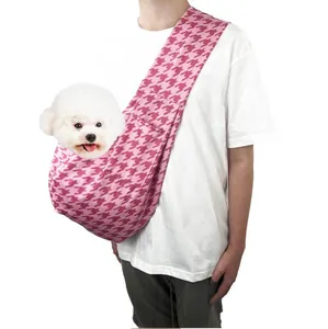 Close-up of pink houndstooth pet sling carrier worn with a small white dog inside