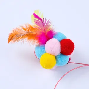 Primer plano de un juguete para gatos con bolas de felpa de colores, plumas y varilla