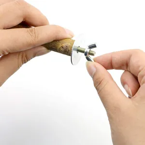 Close-up view showing manual assembly of natural wood bird perch with wing nut and washer.