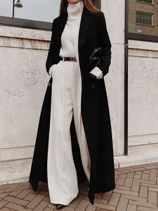 Detailed view of long black wool coat styled with white turtleneck and trousers