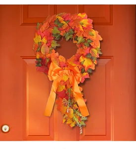 Decorative autumn maple leaf wreath with a vibrant orange bow for harvest festival home decor