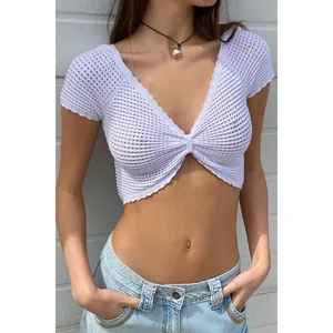 Dettaglio di un crop top bianco lavorato a maglia traforata con scollo a V.