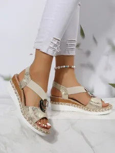Detail view of women's gold snakeskin wedge sandals with rope-trimmed platform sole.