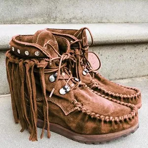 Close-up of brown suede fringe ankle boots with metal studs and lace-up closure