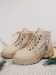 Dettaglio degli stivali invernali beige foderati in pile con cerniera laterale decorativa