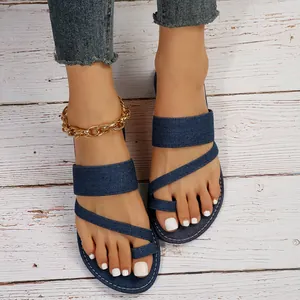Detailansicht modischer Damen-Zehentrenner aus blauem Denim auf rustikalem Holzboden.