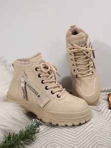 Dettaglio di stivali invernali beige con fodera in peluche e cerniera decorativa.