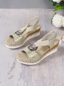 Detail of women's gold snakeskin wedge sandals with rope platform and metal buckle