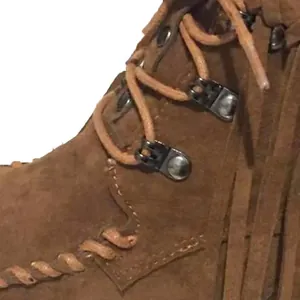 Macro detail view of brown suede fringe ankle boot showing lace-up eyelets and stitching