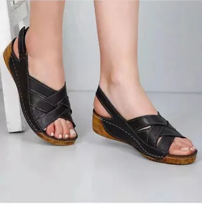 Détail de sandales compensées noires avec brides croisées et coutures blanches