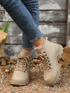 Dettaglio di stivali invernali beige foderati in pile indossati con jeans in denim.