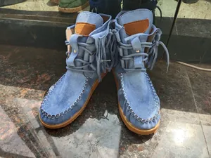 Close-up detail of blue suede fringe ankle boots with lace-up design and thick soles
