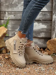 Vista laterale di stivali invernali beige foderati in pile per donna con cerniera decorativa