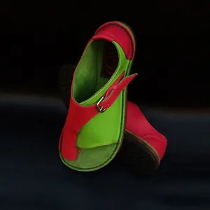 Detail view of red and green color-blocked leather flat sandals with adjustable buckle strap