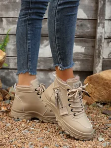 Dettaglio degli stivali invernali alti beige foderati in pile da donna con cerniera decorativa casual
