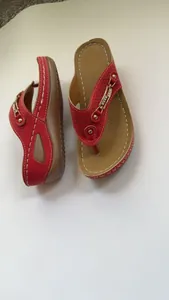 Primer plano de sandalias de cuña rojas con diseño calado y hebillas doradas