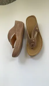 Detalle de sandalias de cuña para mujer en color marrón con tiras perforadas y cadena