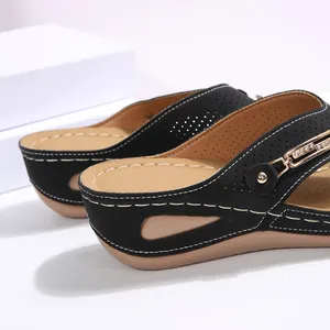 Primer plano de sandalias de cuña negras para mujer con detalle de hebilla de strass