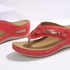 Detalle de sandalias con cuña rojas con hebilla de metal y cristal y pespuntes