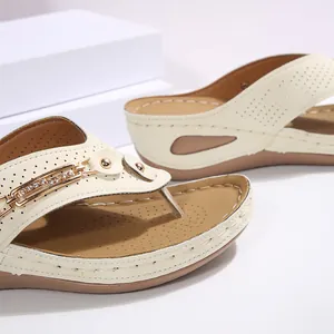 Primer plano de sandalias de cuña crema con elegantes herrajes dorados y calados