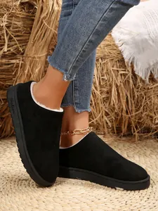 Detail shot of black suede winter snow boots with warm white faux fur lining and flat soles
