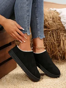 Close-up of black suede snow boots with cozy white faux fur lining and thick rubber sole.
