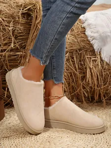 Detailed view of beige fur-lined slip-on winter snow boots styled on a rustic woven mat