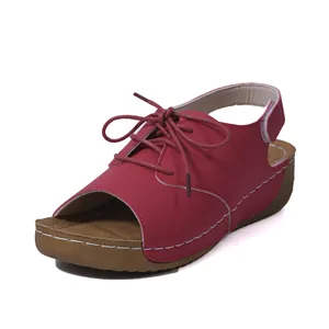 Detailed view of red lace-up peep-toe sandal with thick wedge sole and stitching