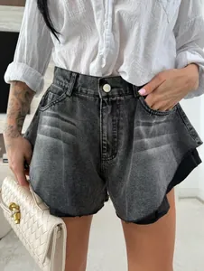 Dettaglio di pantaloncini di denim lavato a vita alta con orlo a vivo e volant