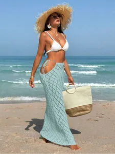 Close-up view of mint green hollow-out knitted maxi skirt with sexy side tie details for beach.